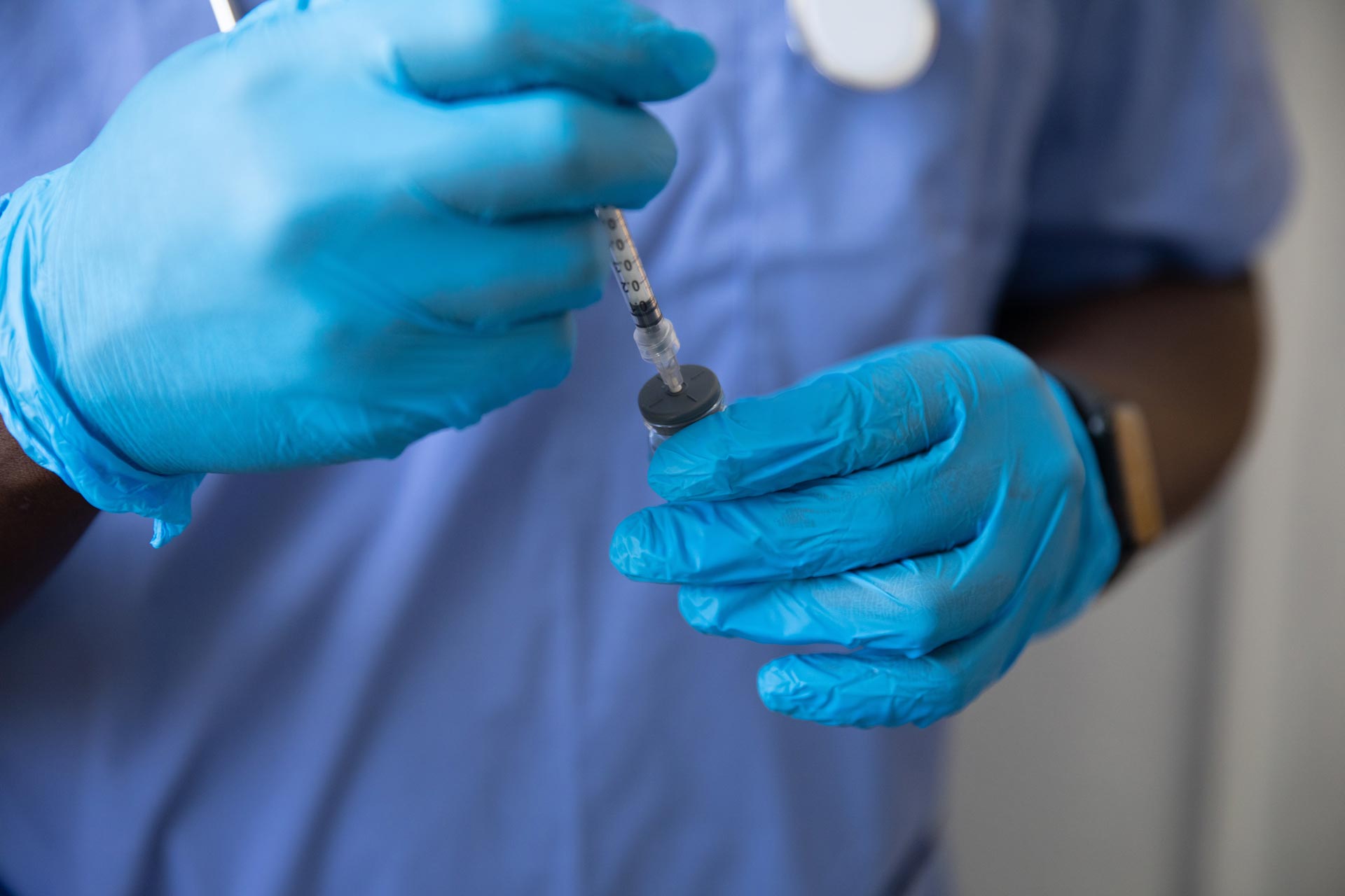 Doctor with blue rubber gloves drawing medicine into a syringe